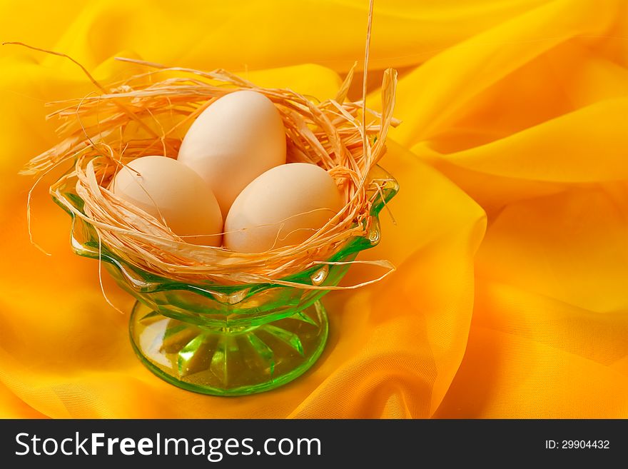 Retro still life with eggs and green glass plate over yellow scarf background