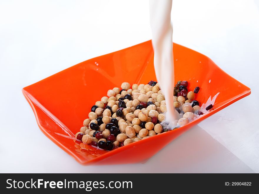 Pouring milk into a bowl with beans. Pouring milk into a bowl with beans