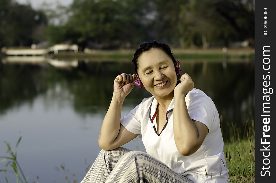 Outdoor portrait of beautiful asian woman listening music in headphones with closed eyes