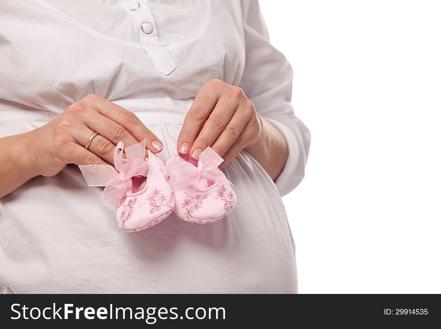 Pregnant woman keeping pink baby-shoes.