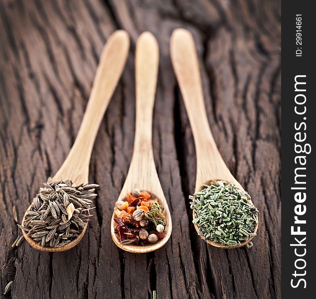 Variety of spices in the spoons on an old wooden table. Variety of spices in the spoons on an old wooden table.