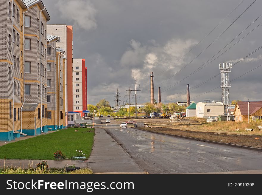 Street with houses, power lines against a cloudy sky. Street with houses, power lines against a cloudy sky.