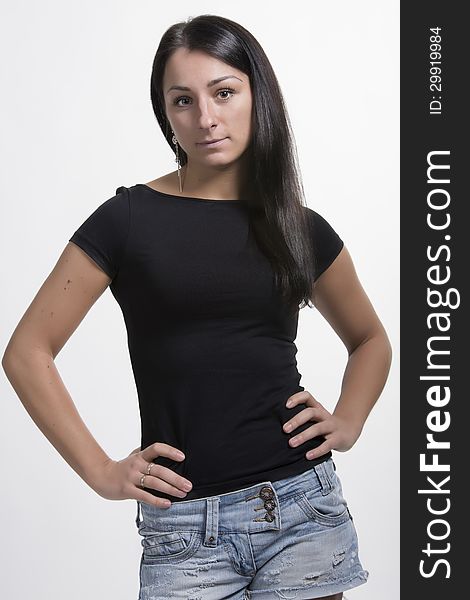 Young woman in black t-shirt standing with arms on hips and looking. Young woman in black t-shirt standing with arms on hips and looking.