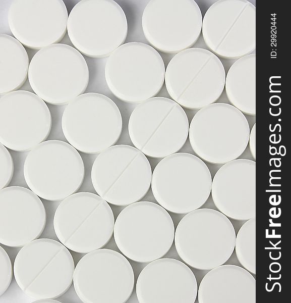 Many of white round pills with diagonal line