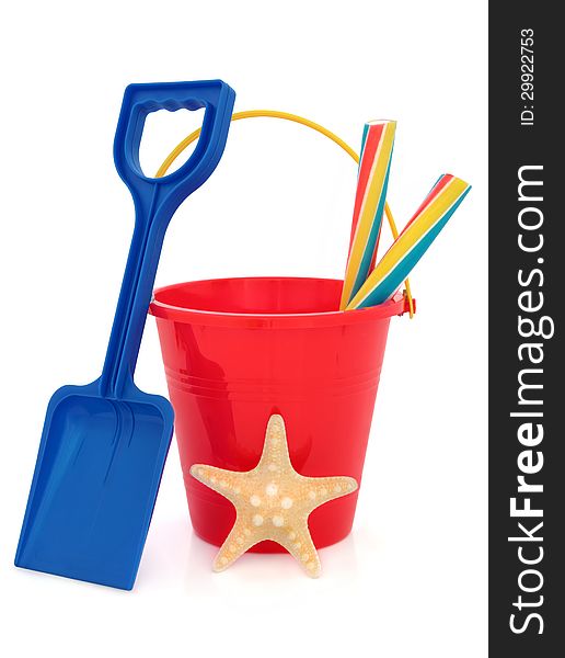 Bucket and spade plastic beach toy in red and blue with stick of rock and starfish over white background. Bucket and spade plastic beach toy in red and blue with stick of rock and starfish over white background.