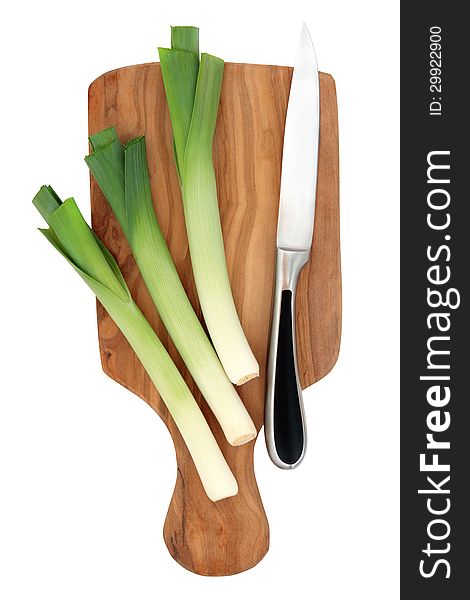 Leek vegetables on an olive wood chopping board with kitchen knife isolated over white background. Leek vegetables on an olive wood chopping board with kitchen knife isolated over white background.