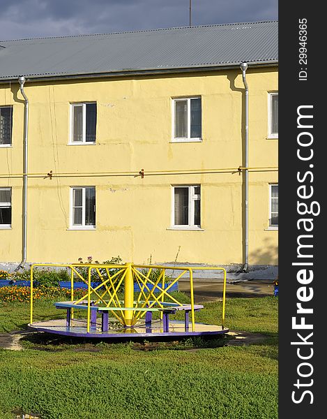 Children's Carousel on the background of the yellow house. Children's Carousel on the background of the yellow house.