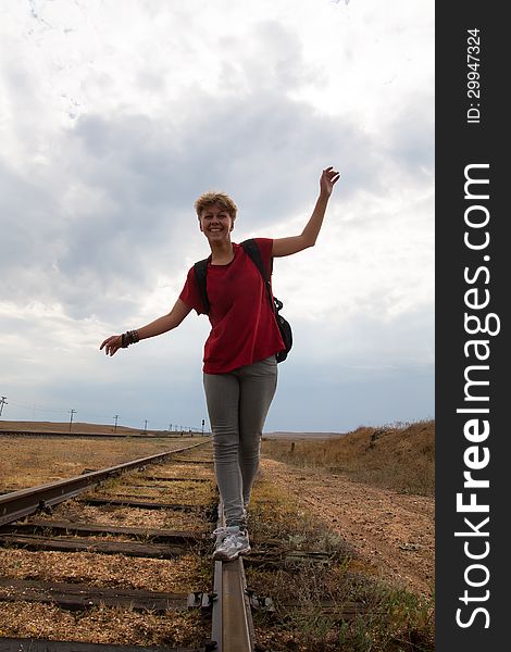 Smiling teen girl walking on old rail road