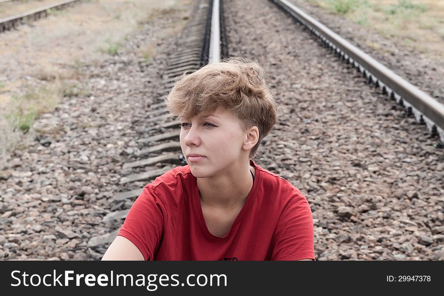 Sad teen girl sitting on rail road