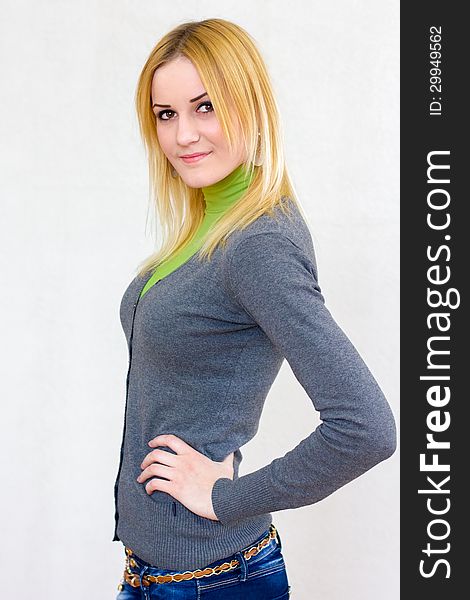 Portrait of a lovely blonde smiling girl with long hair in green turtleneck and gray cardigan