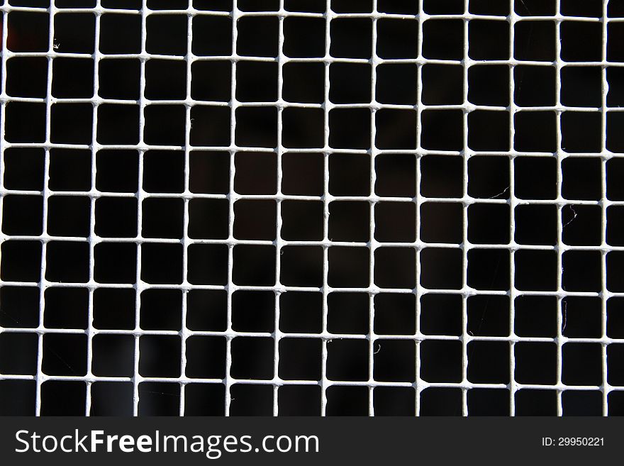 Gray fencing with little squares on dark black background. Gray fencing with little squares on dark black background.