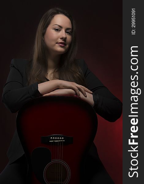 Portrait of young woman with her hands on guitar body, isolated on dark background. Portrait of young woman with her hands on guitar body, isolated on dark background