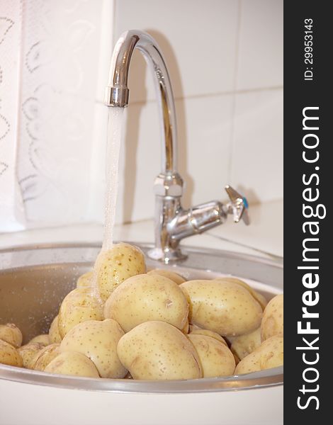 Fresh clean potatoes in a kitchen sink under water