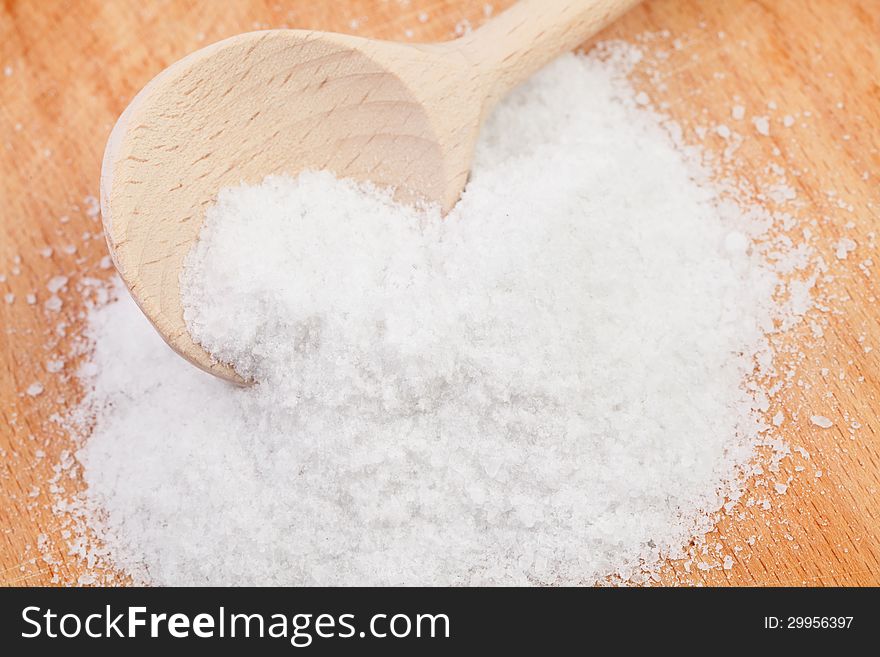 Salt spoon on wooden desk closeup