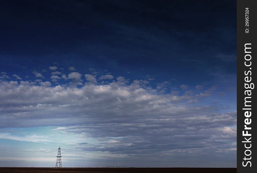 Abandoned Oil Rig Profiled On Cloudy Day Sky