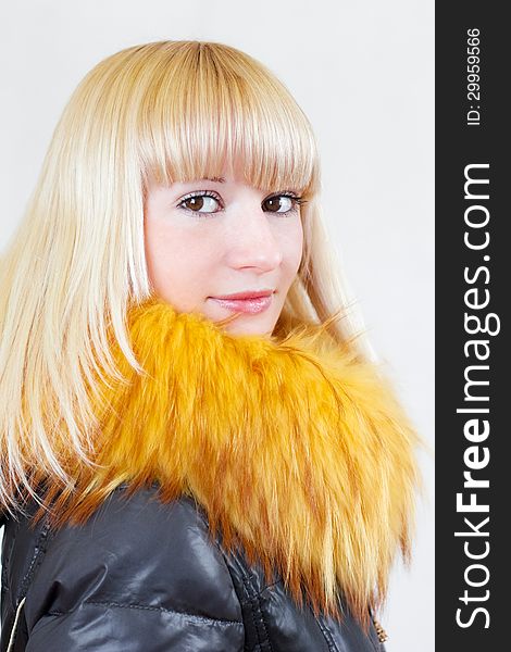 Close-up portrait of a lovely blonde serious girl with long hair in a leather jacket with fur collar