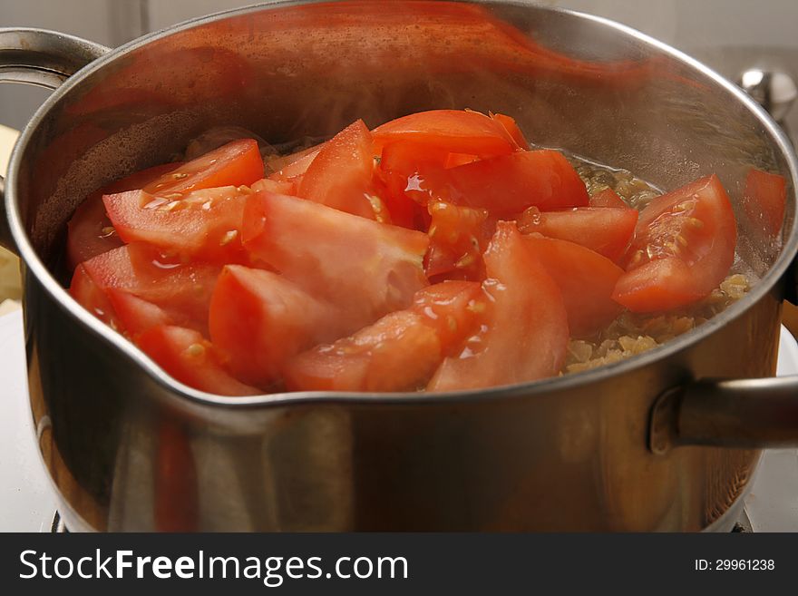 Pieces of tomatoes in a pot boiling with lentil. Pieces of tomatoes in a pot boiling with lentil.