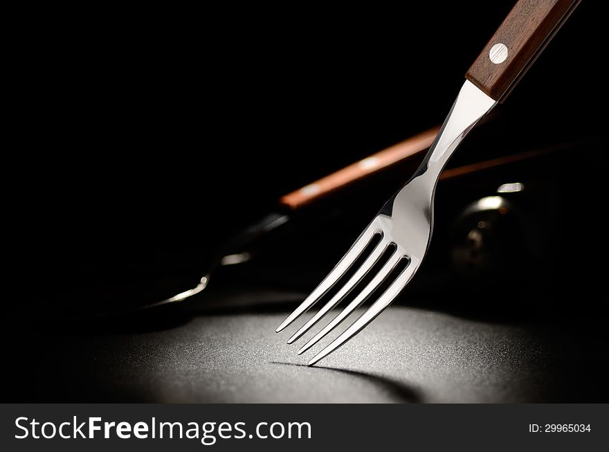 Steel fork on the black grained surface. Steel fork on the black grained surface