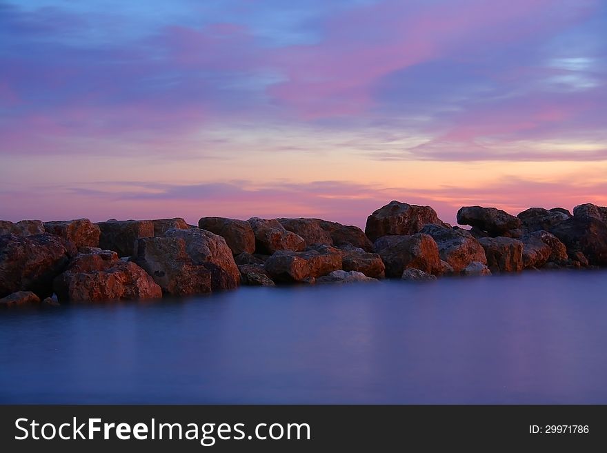 Abstract photo of a group of stones at sunset, shot with long shutter speed to create misty effect in water. Abstract photo of a group of stones at sunset, shot with long shutter speed to create misty effect in water