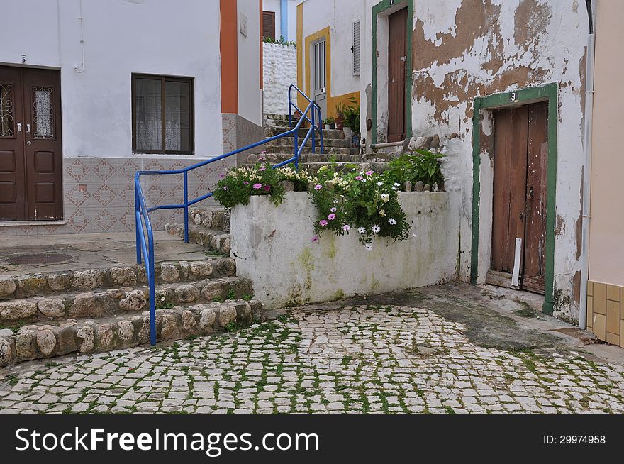 Image shows part of old town Ferragudo, Algarve, Portugal, Europe with blue balustrade and stairs.