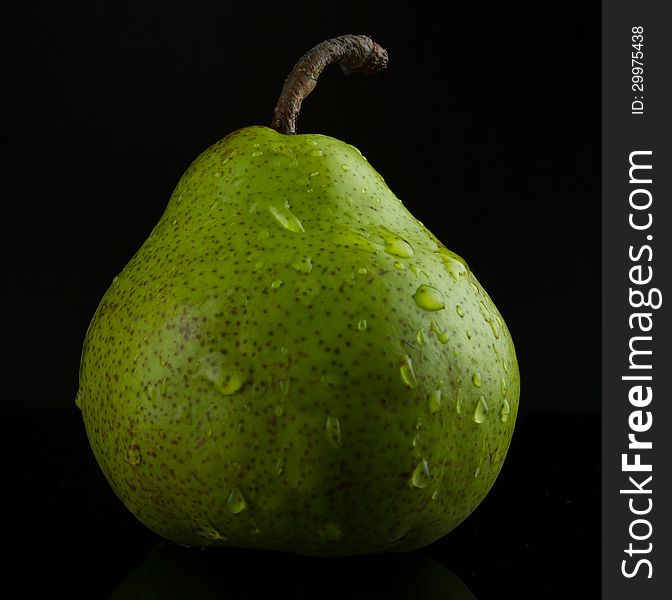 Wet green pear fading into black background. Wet green pear fading into black background