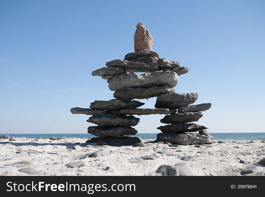 Inukshuk resting on the shoreline with blue sky copy space area