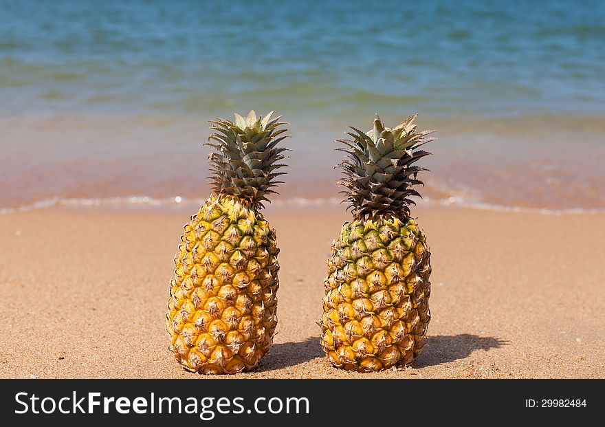 Two pineapples on the beach.