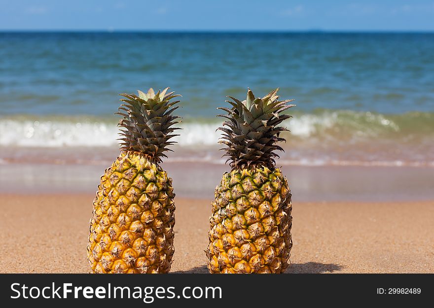 Two pineapples on the beach. Bright sunny day.