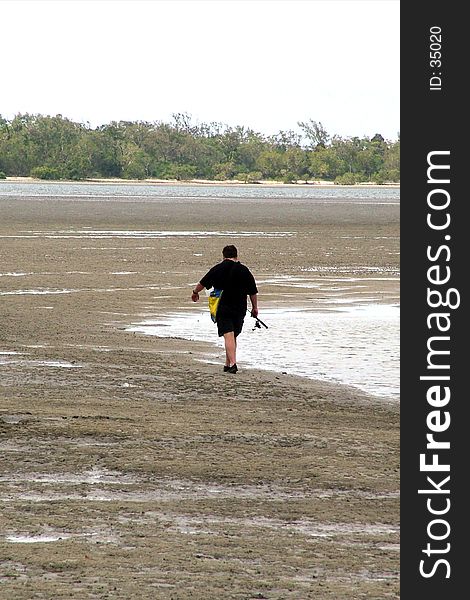 A lone fisherman going out at low tide. A lone fisherman going out at low tide