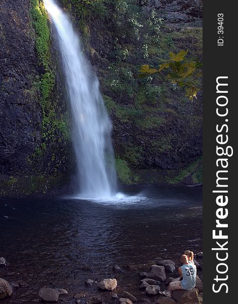 Couple sitting in front of waterfall.