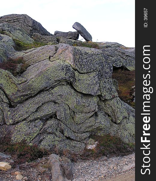 Geologic layers of mountain rock with glacier deposit on top