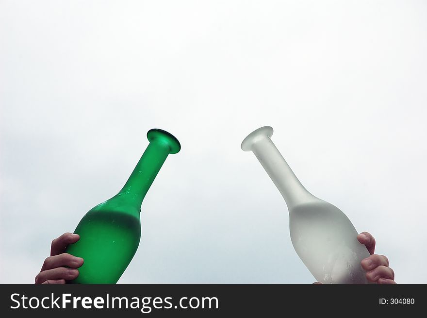 Two glass bottles, one green one white with water inside