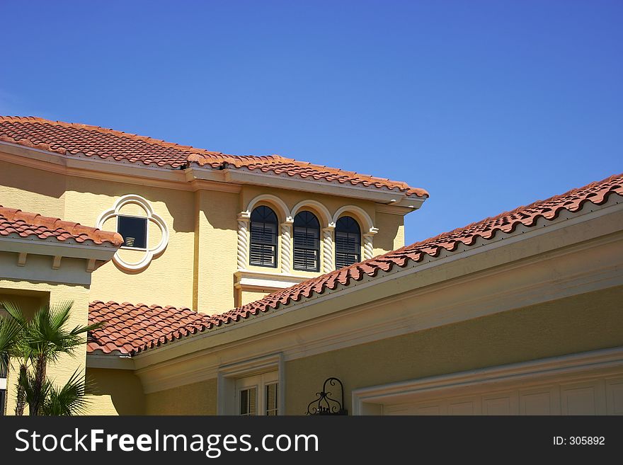 Various angles and levels of tiled roofs against a bright blue sky. Various angles and levels of tiled roofs against a bright blue sky