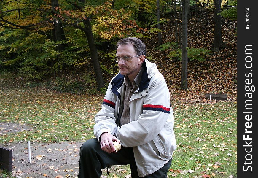 Man with apple in autumn setting, contemplating the scene. Man with apple in autumn setting, contemplating the scene