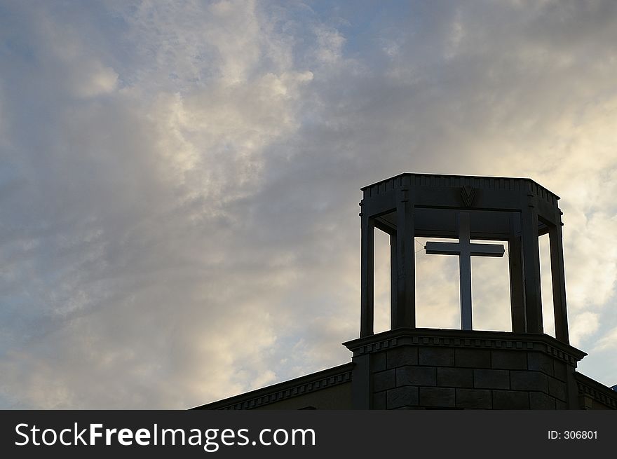 A Christian cross on top of a church with the afternoon sky behind it. A Christian cross on top of a church with the afternoon sky behind it.