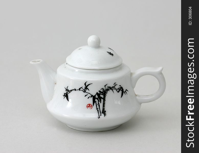 Small China teapot with Chinese bamboo painting on side with white background.