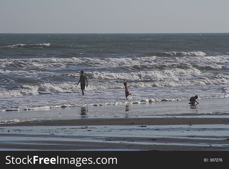 Father & two children playing on the beach and in the surf. Father & two children playing on the beach and in the surf