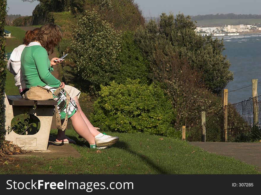 Girls sitting on bench overlooking sea