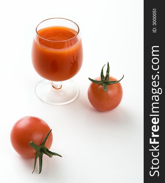 Tomatoes and tomato juice in a glass on a white background