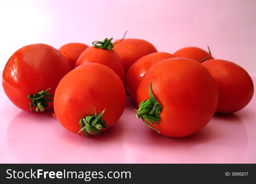 Many tomatoes over pink background