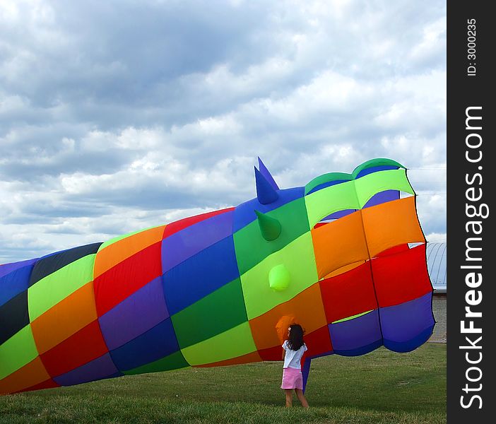 A young girl examines a huge, colorful wind sock kite. A young girl examines a huge, colorful wind sock kite.