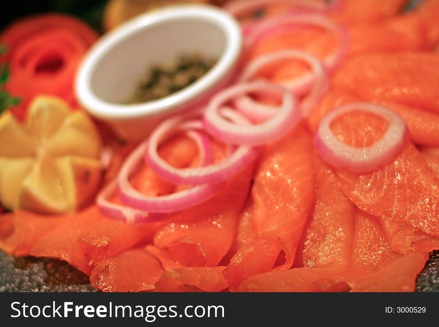 A deli tray of smoked salmon with lemon onions and capers. A deli tray of smoked salmon with lemon onions and capers
