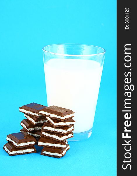 Pouring white milk against blue background and chocolate. Pouring white milk against blue background and chocolate