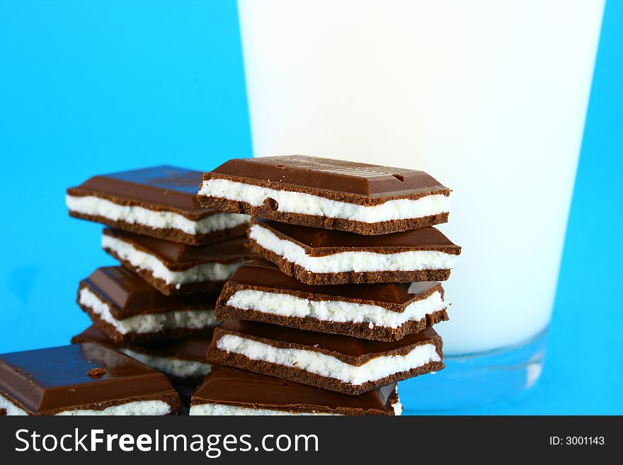 Pouring white milk against blue background and chocolate. Pouring white milk against blue background and chocolate