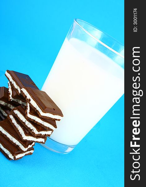 Pouring white milk against blue background and chocolate. Pouring white milk against blue background and chocolate