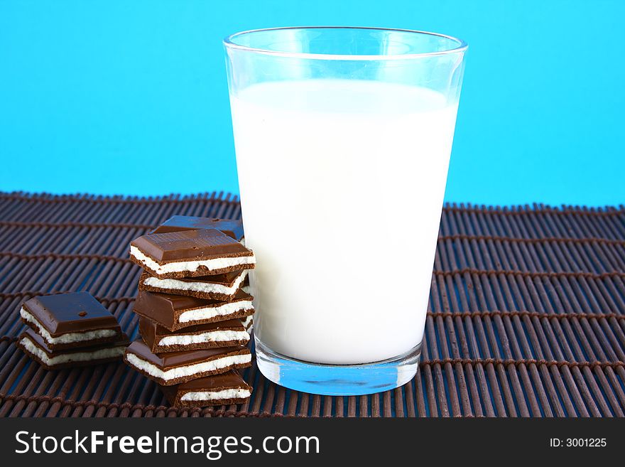 Pouring white milk against blue background and chocolate. Pouring white milk against blue background and chocolate