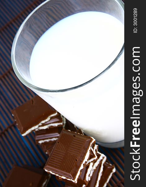 Pouring white milk against blue background and chocolate. Pouring white milk against blue background and chocolate