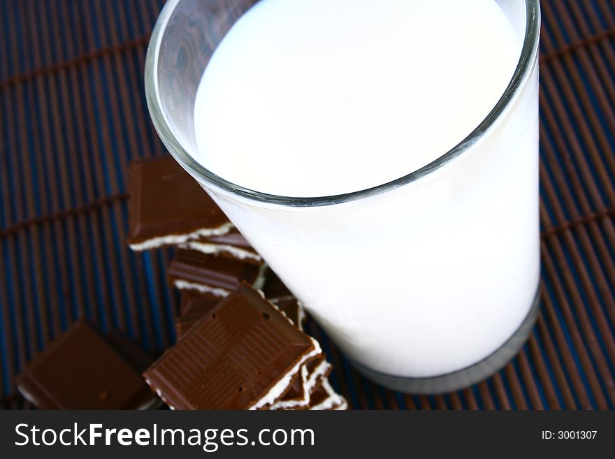 Pouring white milk against blue background and chocolate. Pouring white milk against blue background and chocolate