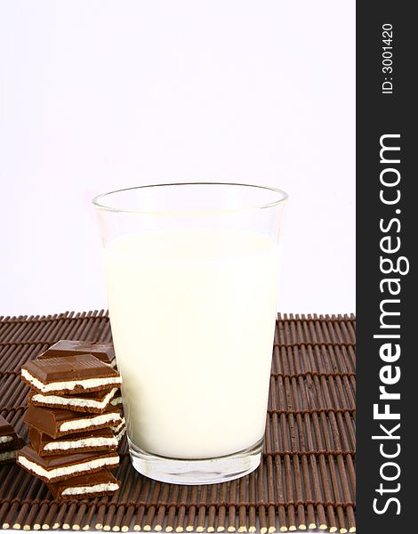 Pouring white milk against blue background and chocolate. Pouring white milk against blue background and chocolate