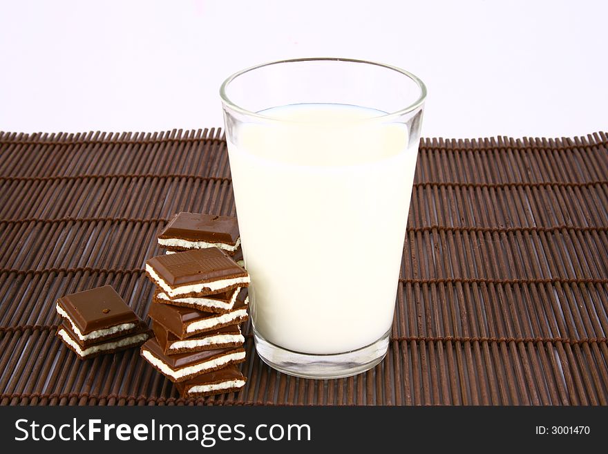 Pouring white milk against blue background and chocolate. Pouring white milk against blue background and chocolate